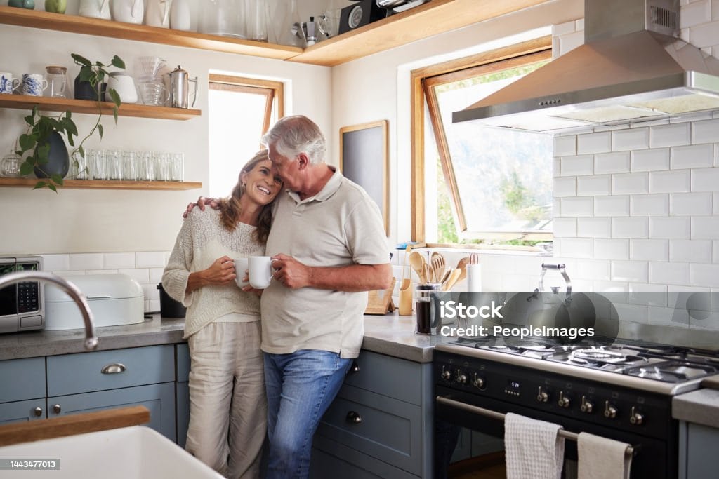 Love, kitchen and senior couple relax with cup of coffee, tea or hot drink while bonding and connect at home. Family, peace and elderly man and woman enjoy quality time, retirement and life together